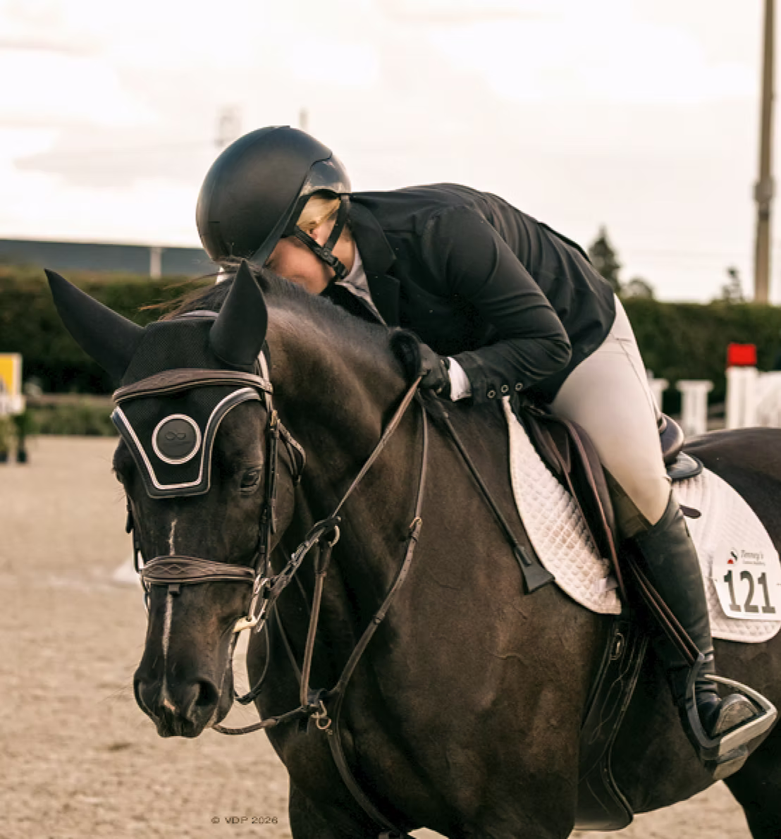 Caitlyn leaning forward to embrace her horse after riding